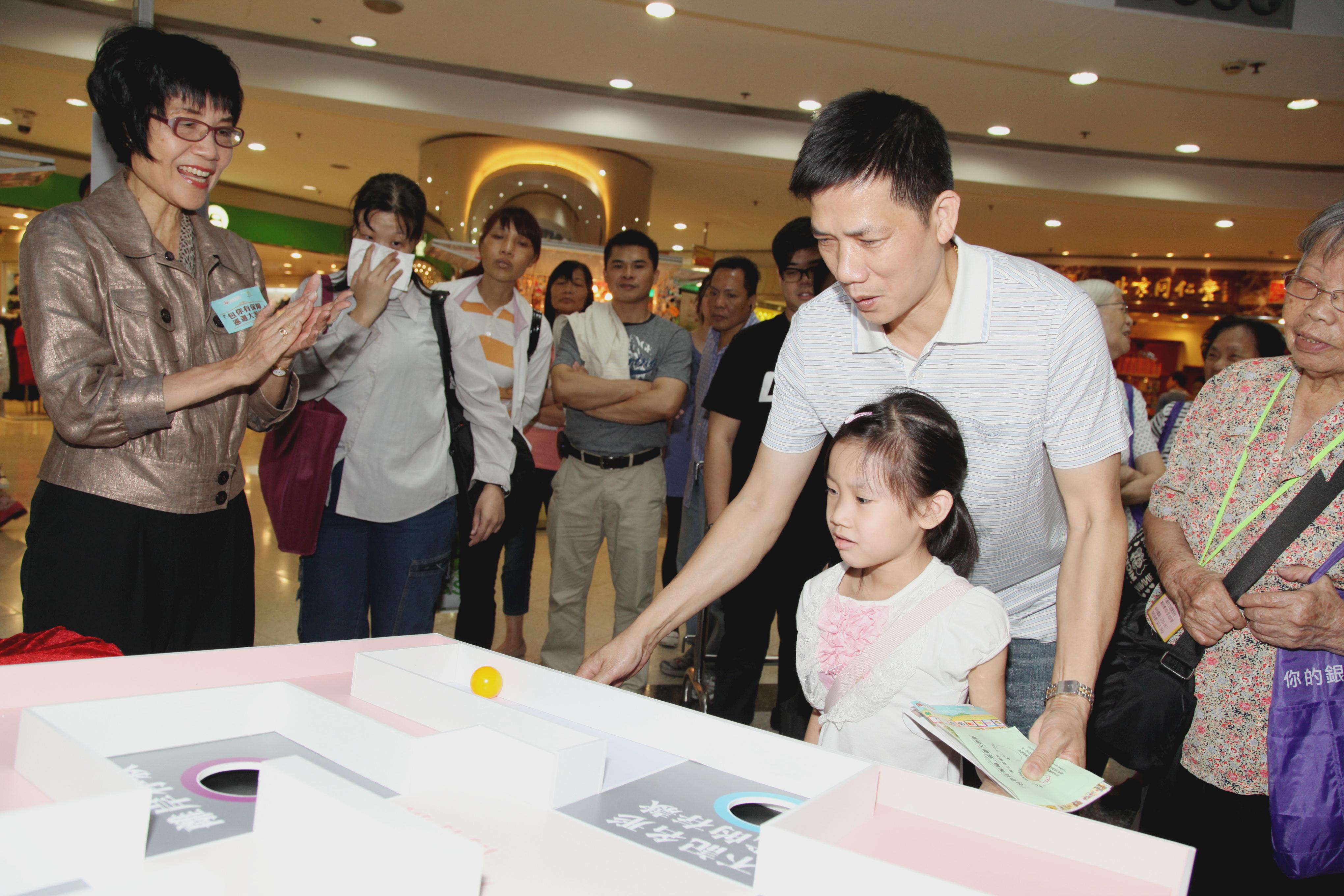 Photo 3: Mrs Pamela Chan, the Chairperson of the Board, tried out at the game booth with the public.